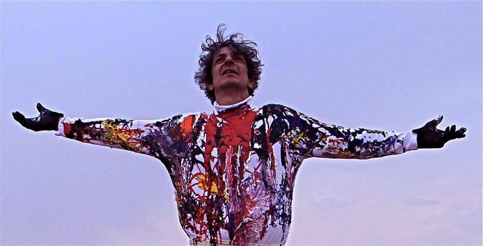 Eternal Braid — a performer with arms outstretched in a paint-covered suit against a pale evening sky