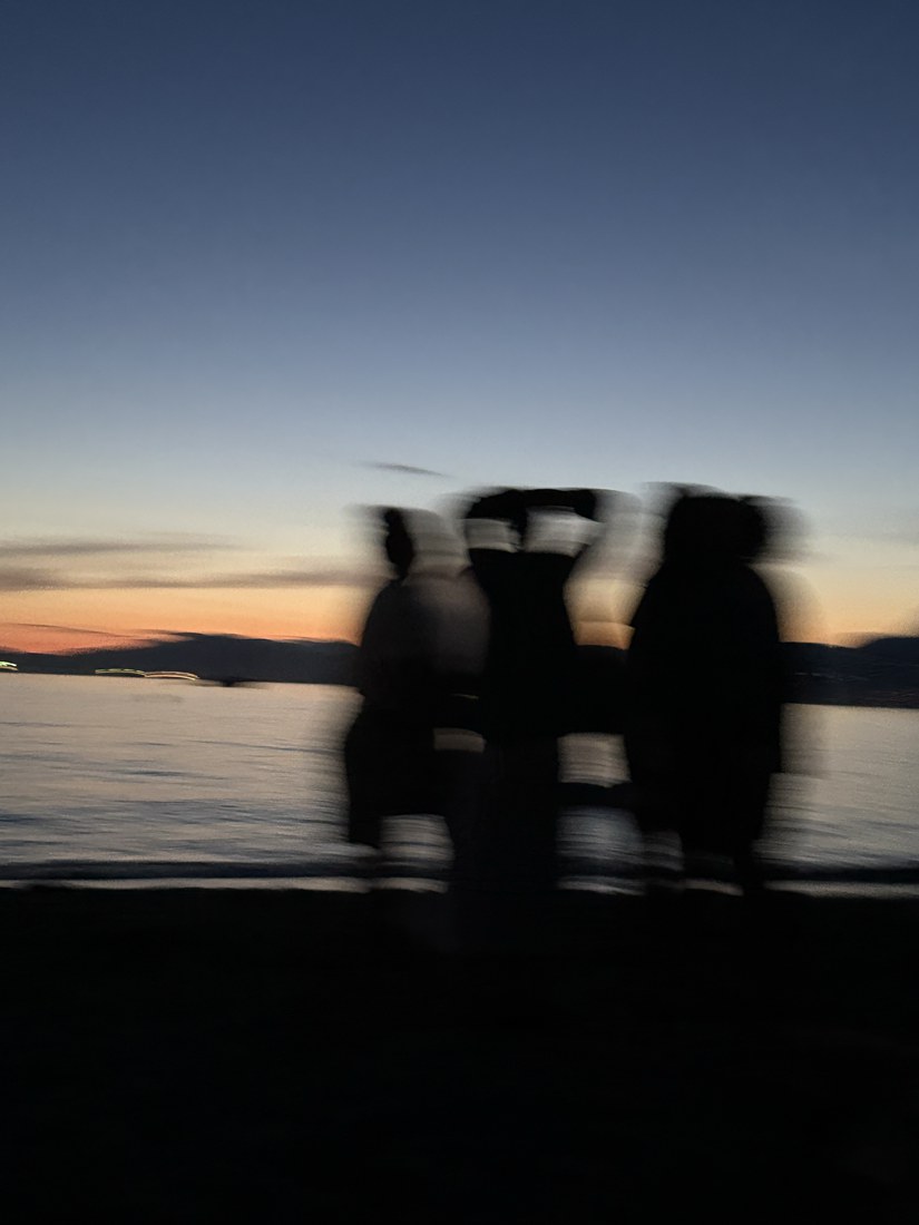 Silhouetted figures blurred against the water at sunset