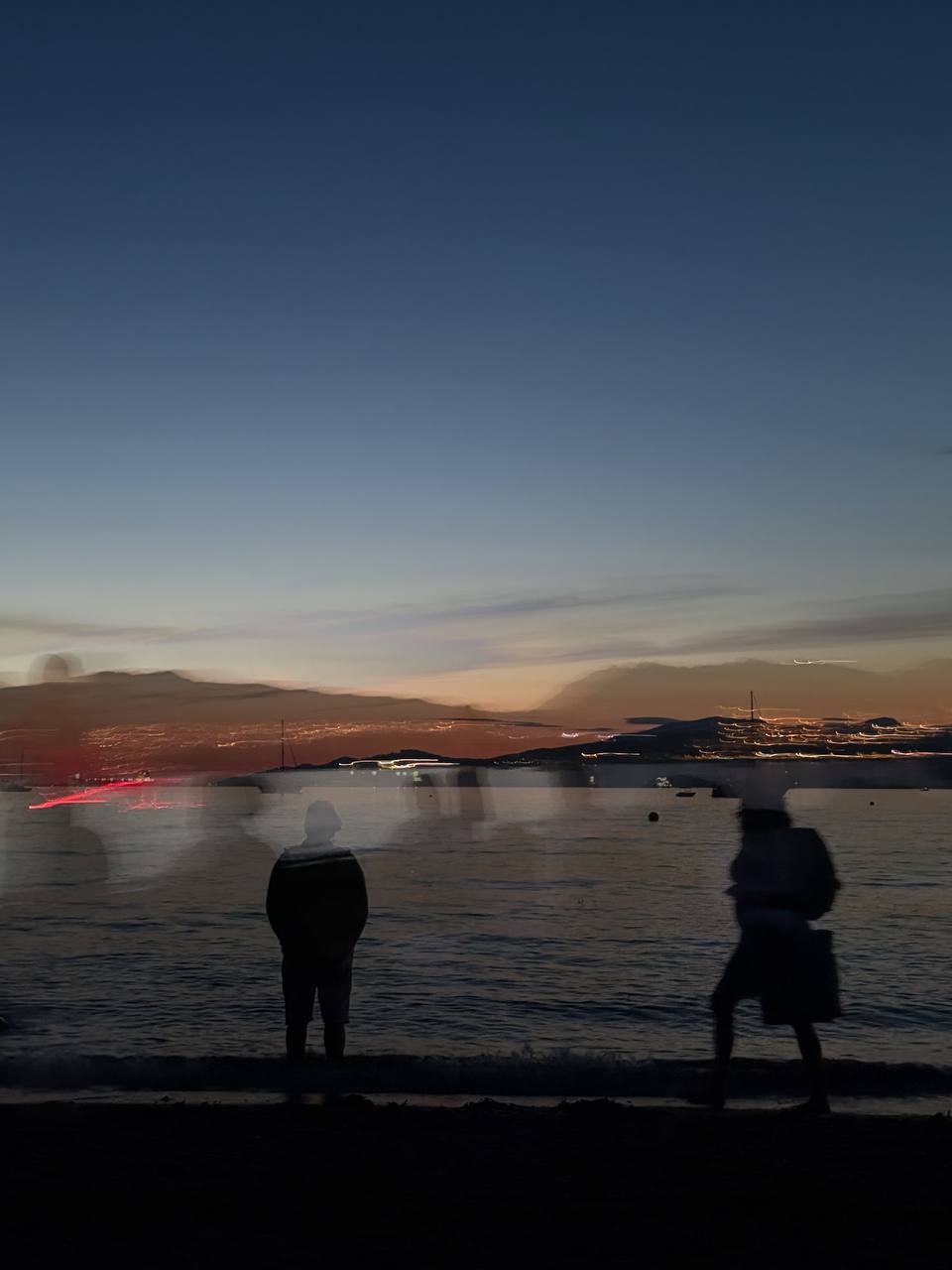 Residue — figures on a shore at dusk, layered with a second image